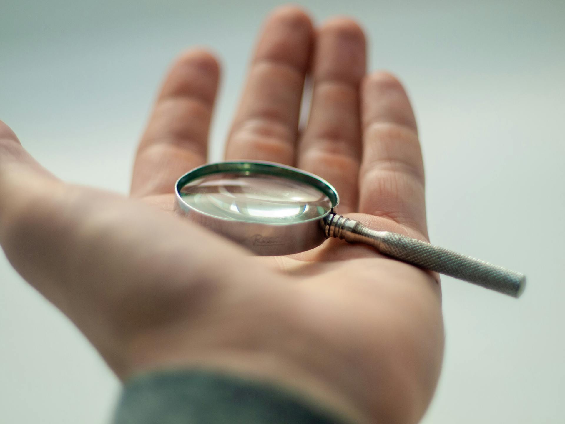 male hand holding a magnifying glass