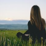 woman wearing black long sleeved shirt sitting on green grass field